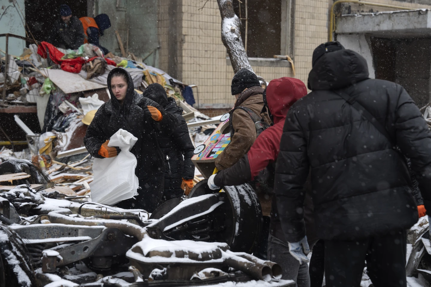 Мешканці забирають свої речі серед уламків свого будинку, сильно пошкодженого під час російської ракетної атаки у вівторок у Києві, Україна, середа, 3 січня 2024 року